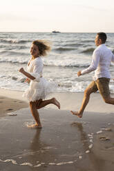 Girlfriend and boyfriend running at beach by sea - SSGF00097