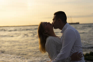 Boyfriend kissing girlfriend at beach on sunset - SSGF00102