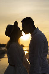 Girlfriend rubbing nose with boyfriend at beach on sunset - SSGF00110
