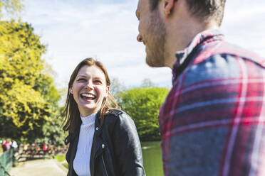 Happy woman talking to friend in park - WPEF05459