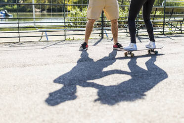 Mädchen lernt mit einem Freund im Park das Skateboardfahren - WPEF05461
