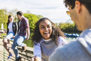 Laughing woman looking at man on sunny day in park - WPEF05463