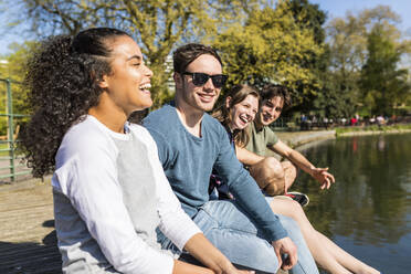 Lachende Frau mit Freunden an einem sonnigen Tag im Park - WPEF05469