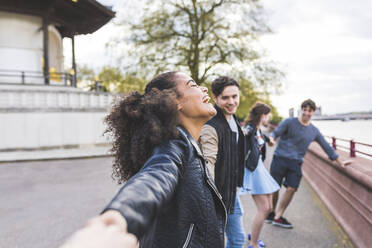 Laughing woman holding hands of friends in park - WPEF05488