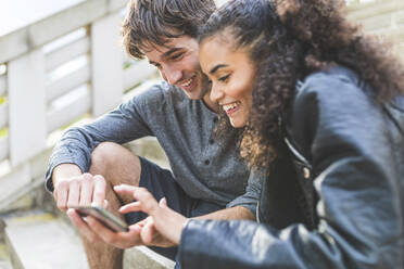 Aufgeregte Freunde benutzen ihr Smartphone auf der Treppe - WPEF05493