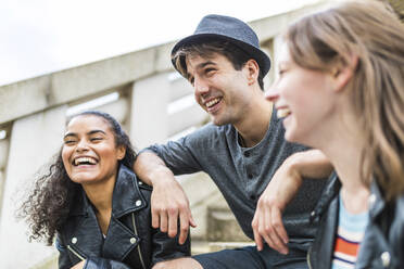 Young man with hat leaning on cheerful friends - WPEF05495