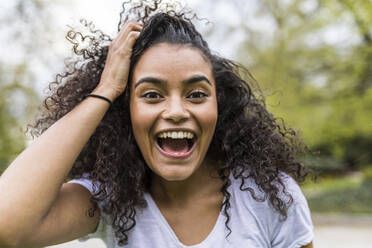 Happy woman with head in hand screaming at park - WPEF05501