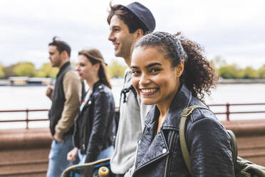 Young woman in leather jacket walking with friends - WPEF05505