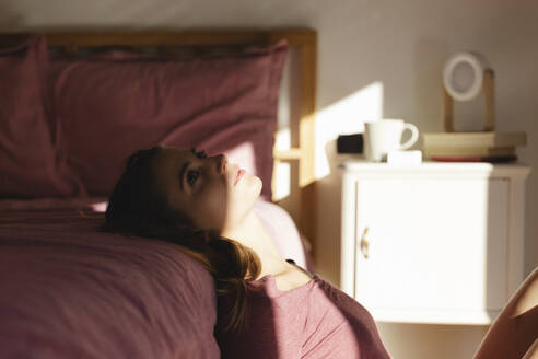 Junge Frau in Depression lehnt auf dem Bett im Schlafzimmer - MRAF00650