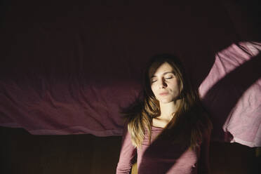 Junge depressive Frau mit geschlossenen Augen lehnt zu Hause auf dem Bett - MRAF00652