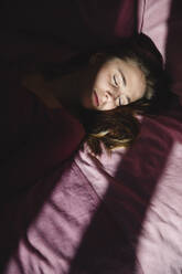 Depressed young woman with eyes closed lying on bed - MRAF00659
