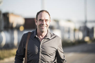 Cheerful businessman with gray shirt on street - UUF24942