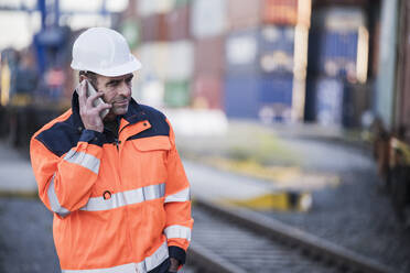 Männlicher Arbeiter spricht am Dock mit seinem Smartphone - UUF24958