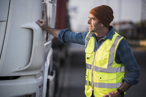 Male driver standing by truck at commercial dock - UUF24970