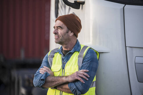 Thoughtful male driver with arms crossed in front of truck - UUF24979