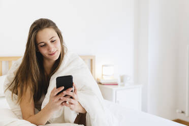 Smiling young woman with brown hair using smart n bed - MRAF00686