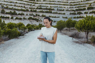 Eine Wissenschaftlerin schreibt in einem Buch, während sie in einem alten Bergwerk steht - DMGF00577