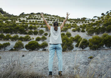 Woman standing with arms raised at old mine - DMGF00597