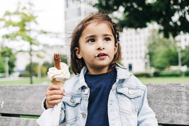 Nettes Mädchen mit braunen Haaren hält Eiswaffel im Park - ASGF01664