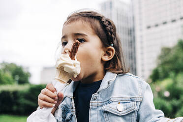 Girl eating ice cream at public park - ASGF01665
