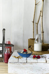 Bowl of muesli and bottle of milk standing on wooden surface - ASF06779