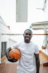 Lächelnder Mann mit Basketball aus dem Haus - PGF00859