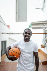 Smiling man with basketball out of house - PGF00859