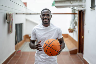 Smiling young man holding basketball - PGF00861