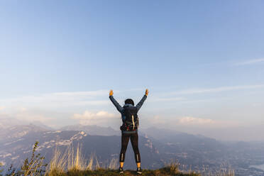 Carefree woman with arms raised on mountain peak - MRAF00723