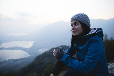 Junger Wanderer mit Kaffeetasse auf einem Berg - MRAF00745