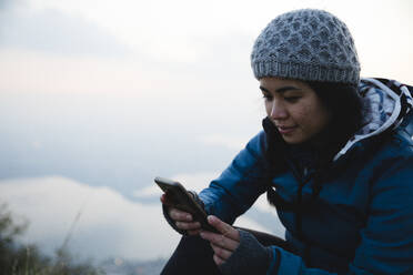 Wanderer mit Smartphone bei Sonnenuntergang - MRAF00751