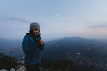 Wanderer mit Blick auf Kaffeetasse auf Berg - MRAF00754