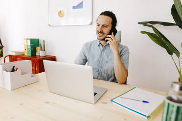 Businessman talking on mobile phone in office - TCEF02074