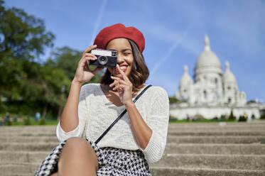 Female tourist photographing through camera at Basilique Du Sacre Coeur, Montmartre in Paris, France - KIJF04245