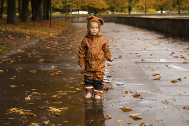 Mädchen mit braunem Regenmantel steht auf der Straße - SSGF00116