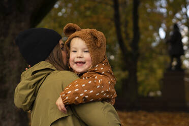 Mother hugging daughter in autumn park - SSGF00158