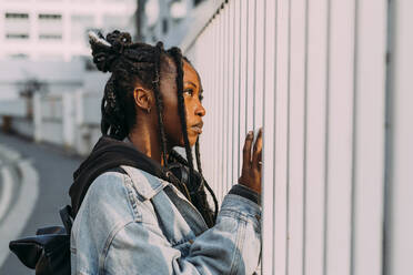 Woman with bag looking through fence - MEUF04562