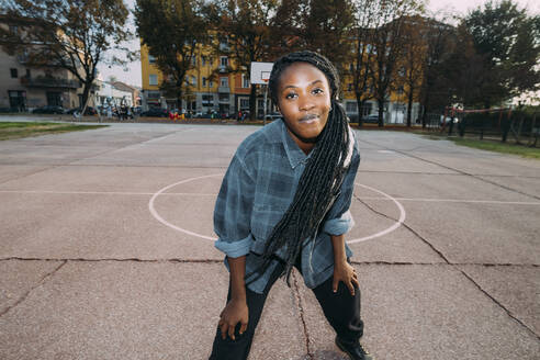 Lächelnde Frau mit Locus-Frisur auf dem Basketballplatz - MEUF04591