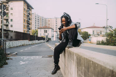 Smiling woman using mobile phone on wall - MEUF04613