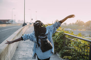 Carefree woman with arms outstretched on footpath - MEUF04618