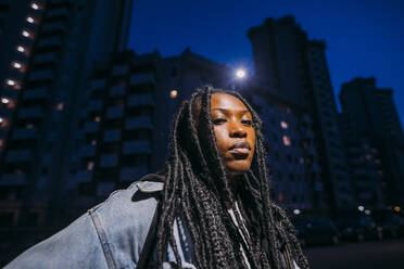 Young woman with hair locs in city at night - MEUF04657
