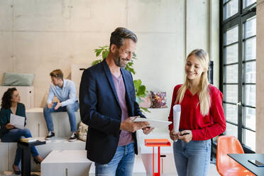 Businessman discussing over tablet computer with colleague in office - DIGF16603