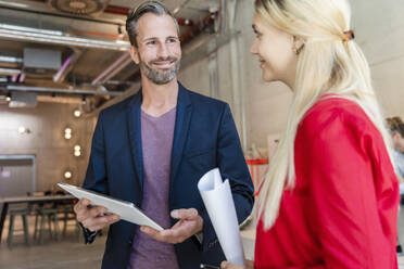 Businessman holding tablet PC while working with female coworker in office - DIGF16607