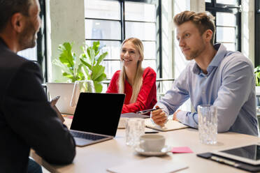 Young coworkers listening to businessman in meeting - DIGF16637