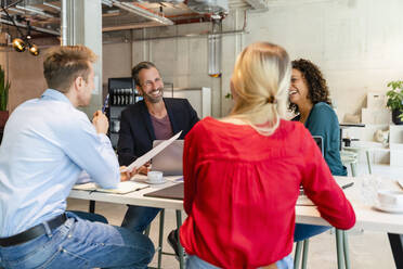 Smiling coworkers having discussion at office desk - DIGF16640