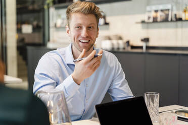 Smiling young businessman discussing with colleague in office - DIGF16642