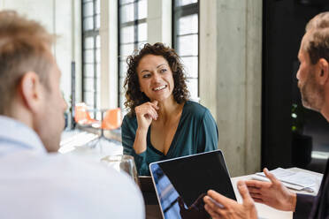 Smiling businesswoman listening to coworker in meeting - DIGF16646