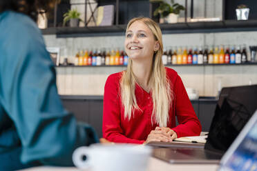 Blonde Geschäftsfrau schaut einen Kollegen im Büro an - DIGF16668