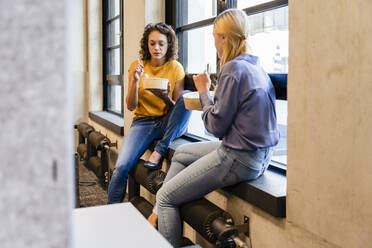 Businesswoman having lunch with colleague in office - DIGF16694