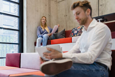 Businesswoman with document looking at colleague in office - DIGF16768